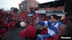 El presidente venezolano y candidato presidencial, Hugo Chávez, saluda a sus partidarios desde un vehículo durante un acto de campaña en San Fernando de Apure el 15 de septiembre de 2012. 