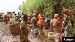 Quelques femmes se tiennent sur les hauteurs boueuses de Masisi après des pluies dans le nord de Goma, Nord-Kivu, 4 octobre 2013.