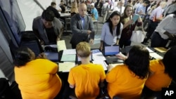 FILE - Job candidates are processed during a job fair at the Amazon fulfillment center in Robbinsville Township, N.J., Aug. 2, 2017. 