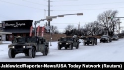 Military vehicles from the Texas Military Department of the Texas National Guard, tasked to transport residents to designated warming centers and other required duties, form a convoy in Abilene, Texas, U.S. February 16, 2021. Greg Jaklewicz/Reporter-News/