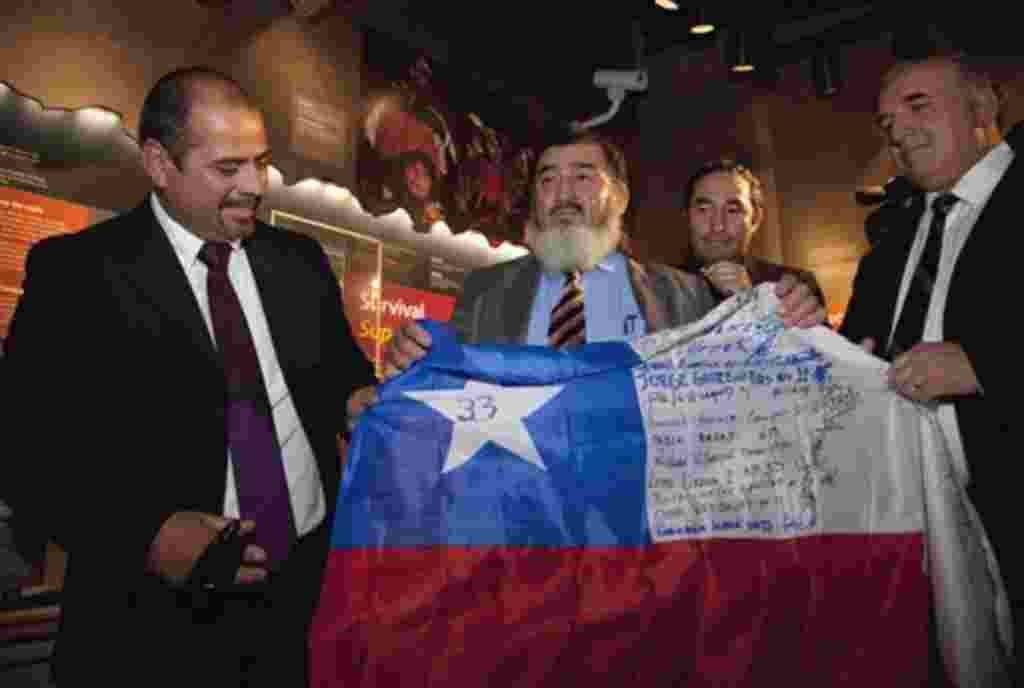 Los mineros chilenos Mario Sepúlveda, Gallegillos Jorge, Carlos Barrios y José Henríquez sostienen una bandera durante la inauguración de la exposición “Contra los obstáculos”.