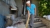 Natalia, 51, wounded by a Russian missile attack on Monday that damaged her house, sweeps wreckage from blood-stained steps in the village of Kindrashchivka, Kharkiv region, July 16, 2024. 