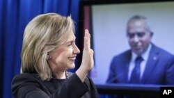 State Secretary Hillary Rodham Clinton waves to Palestinian PM Salam Fayyad, seen on a video monitor, during a video conferencing at the State Department in Washington, announcing the transfer of budget assistance funds to the Palestinian Authority, 10 No