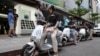 In this Monday, June 15, 2015, photo, Gogoro electric scooters are test driven by potential customers outside a showroom in Taipei, Taiwan.