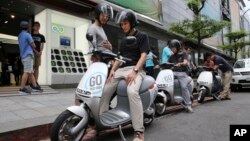 In this Monday, June 15, 2015, photo, Gogoro electric scooters are test driven by potential customers outside a showroom in Taipei, Taiwan.