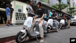 In this Monday, June 15, 2015, photo, Gogoro electric scooters are test driven by potential customers outside a showroom in Taipei, Taiwan.