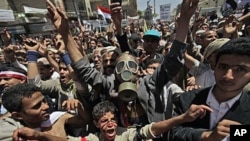 An anti-government protester, center, wearing a gas mask, chants slogans along with others during a demonstration demanding the resignation of Yemeni President Ali Abdullah Saleh, in Sanaa,Yemen, March 21, 2011