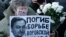 FILE - A woman holds a placard with a portrait of Sergei Magnitsky during an unauthorized rally in central Moscow, Dec. 15, 2012. The placard reads "Died fighting a system of thievery."