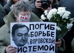 FILE - A woman holds a placard with a portrait of Sergei Magnitsky during an unauthorized rally in central Moscow December 15, 2012. The placard reads "Died fighting a system of thievery."