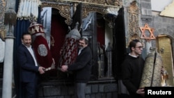 Henry Hamra and members of a Syrian Jewish delegation who are visiting Syria for the first time in decades hold a Torah case at a synagogue in Damascus, Syria, Feb. 18, 2025.