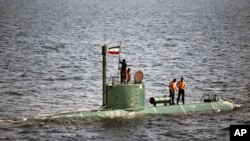 Military personnel place a flag on a submarine during the Velayat-90 war games by the Iranian navy in the Strait of Hormuz in southern Iran December 27, 2011