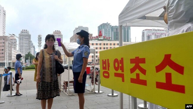 지난 2020년 8월 북한 평양역에서 신종 코로나바이러스 방역을 위해 직원이 이용객의 체온을 재고 있다.