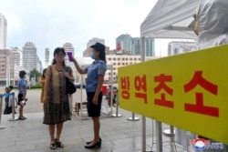 FILE - A station employee checks the temperature of a passenger to help prevent the spread of COVID-19, in Pyongyang, in this undated picture released from North Korea's official Korean Central News Agency on Aug. 29, 2020. (KCNA via KNS / AFP)