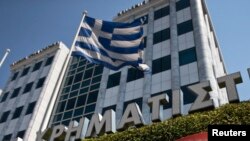 FILE - A Greek flag flutters outside the Athens stock exchange, Greece.