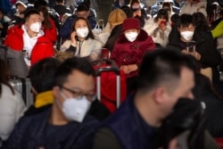 Travelers wear face masks as they sit in a waiting room at the Beijing West Railway Station in Beijing, Jan. 21, 2020.