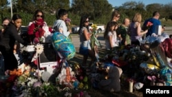 Well-wishers place flowers the day students and parents arrive for voluntary campus orientation at the Marjory Stoneman Douglas High School, Feb. 25, 2018. The school reopens Wednesday, following the Valentine's Day mass shooting in Parkland, Florida.