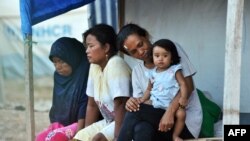 Ibu-ibu dan seorang anak perempuan duduk di depan tenda merea di hunian sementara di Palu, Sulawesi Tengah, 25 September 2019, sebagai ilustrasi. (Foto: AFP)