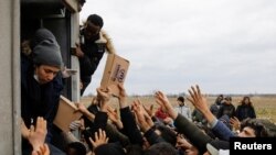 FILE - Members of United Nations High Commissioner for Refugees deliver food to migrants at Turkey's Pazarkule border crossing with Greece's Kastanies, in Edirne, Turkey, Feb. 29, 2020. 