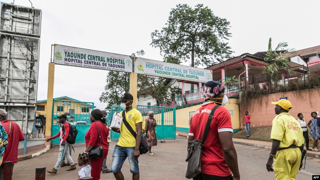 Some people wear masks as they walk by the entrance to the Yaounde General Hospital in Yaounde, March 6, 2020, as Cameroon has confirmed its first case of the COVID-19 coronavirus.