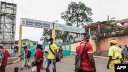 Some people wear masks as they walk by the entrance to the Yaounde General Hospital in Yaounde, March 6, 2020, as Cameroon has confirmed its first case of the COVID-19 coronavirus.