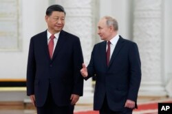 Presiden Rusia Vladimir Putin, kanan, berbicara kepada Presiden China Xi Jinping saat mereka menghadiri upacara penyambutan resmi di The Grand Kremlin Palace, di Moskow, Rusia, 21 Maret 2023. (Foto: via AP)