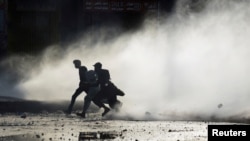 Supporters of the Tehreek-e-Labaik Pakistan (TLP) Islamist political party run to cover amid water jet during a protest against the arrest of their leader in Lahore, Pakistan, April 13, 2021.