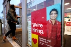 FILE - A woman walks past a hiring sign at a Target store, in Westwood, Massachusetts, Feb. 9, 2021.