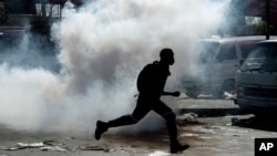 A man runs away from tear gas after making off with goods from a store in Germiston, east of Johannesburg, South Africa, Sept. 3, 2019. 