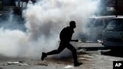 A man runs away from tear gas after making off with goods from a store in Germiston, east of Johannesburg, South Africa, Sept. 3, 2019. 