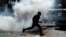 A man runs away from tear gas after making off with goods from a store in Germiston, east of Johannesburg, South Africa, Sept. 3, 2019. 