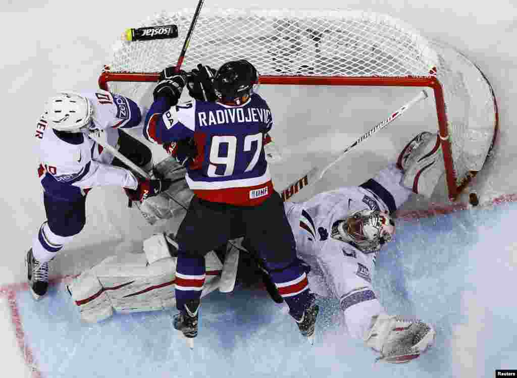 Pemain Slovakia, Branko Radivojevic (tengah) berupaya untuk mencetak gol melewati pemain Perancis Laurent Meunier (kiri) dan Kiper Cristobal Huet dalam pertandingan putaran awal kejuaraan dunia Hockey Es IIHF 2013 di Hartwall Arena di&nbsp; Helsinki, Finlandia.