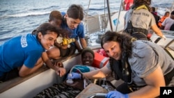 Doctors tend to a pregnant woman on a Mediterranea Saving Humans NGO boat, as they sail off Italy's southernmost island of Lampedusa, just outside Italian territorial waters, July 4, 2019. 