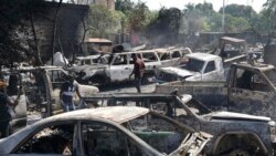 Sejumlah orang mencari barang-barang yang masih bisa diselamatkan dari mobil-mobil yang hangus dibakar massa saat kekerasan oleh geng-geng bersenjata di Port-au-Prince, Haiti, 25 Maret 2024. (Foto: Odelyn Joseph/AP Photo)