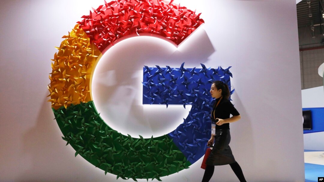 FILE - A woman walks past the logo for Google at the China International Import Expo in Shanghai, Nov. 5, 2018.