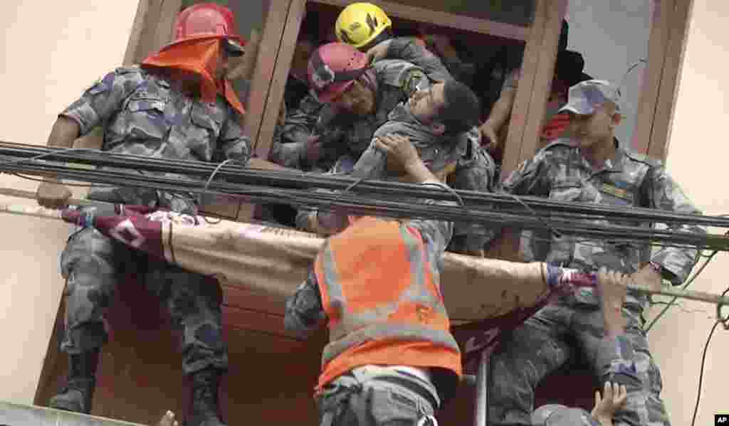 In this image made from video, rescue workers pull a survivor from an earthquake damaged building in Kathmandu, Nepal.