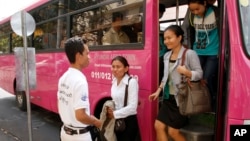 Cambodian passengers disembark from a bus as Phnom Penh begins its trial for public bus service, Wednesday, Feb. 5, 2014, in Phnom Penh, Cambodia. 