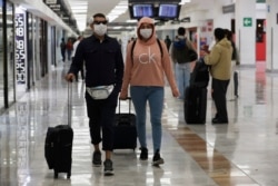 A couple wears protective masks as a precaution against the spread of the new coronavirus at the airport in Mexico City, Feb. 28, 2020.
