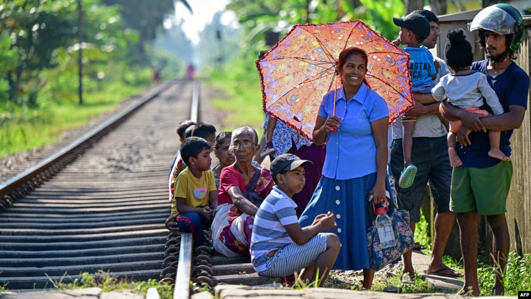 People wait for the arrival of the Ocean Queen train carrying family members of people killed in the 2004 Indian Ocean tsunami, for a memorial service in Peraliya on Dec. 26, 2024, on the 20th anniversary of the disaster. 