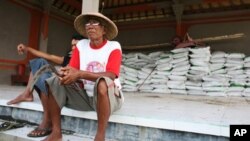 Farmers in Indonesia sitting in front of processed rice that is ready to be sold. Economists say rice farmers living below the poverty line could be the most vulnerable to the impact of floods in Southeast Asia.