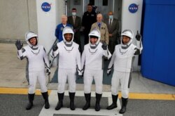 Los miembros de la tripulación de un cohete SpaceX Falcon 9, comandante Mike Hopkins, Victor Glover, Shannon Walker y el astronauta japonés Soichi Noguchi, gesticulan mientras parten hacia la plataforma de lanzamiento en el Centro Espacial Kennedy.