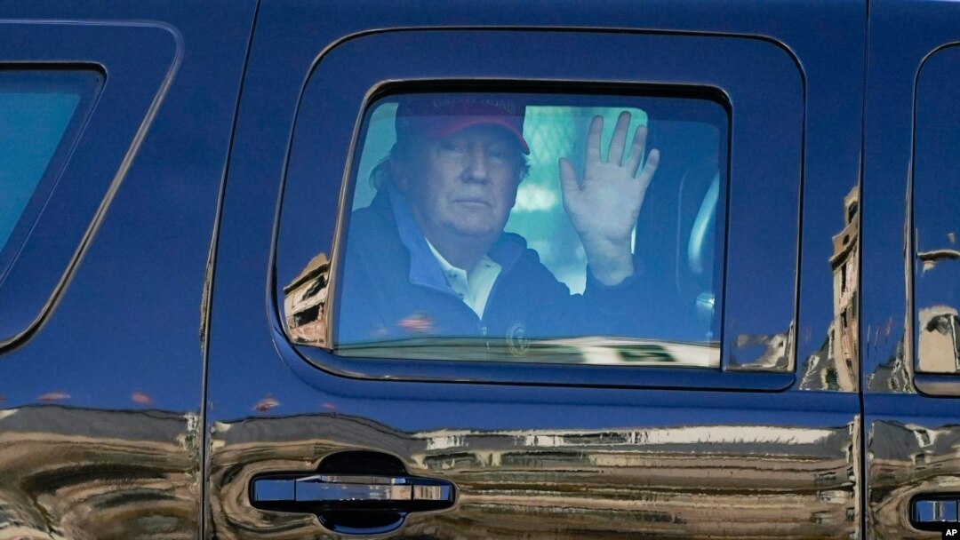 President Donald Trump waves to supporters from his motorcade as people gather for a march, Nov. 14, 2020.
