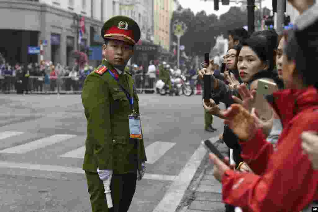 یک مامور گارد امنیتی مقابل مردمی که در پیاده رو در انتظار عبور پرزیدنت ترامپ و کیم جونگ اون در صبح پنجشنبه در هانوی ویتنام هستند، ایستاده است.