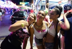 FILE - Tourists react as they pose for a photo at the resort of Magaluf, in Calvia town, on the Spanish Balearic island of Mallorca, June 10, 2015.