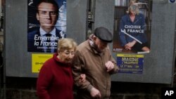 A couple walks past election posters near a polling station in Paris, France, May 7, 2017. With parliamentary elections looming, mainstream leftists and rightists now struggle to adjust to the new political landscape created by a centrist candidate’s victory in Sunday's presidential poll.