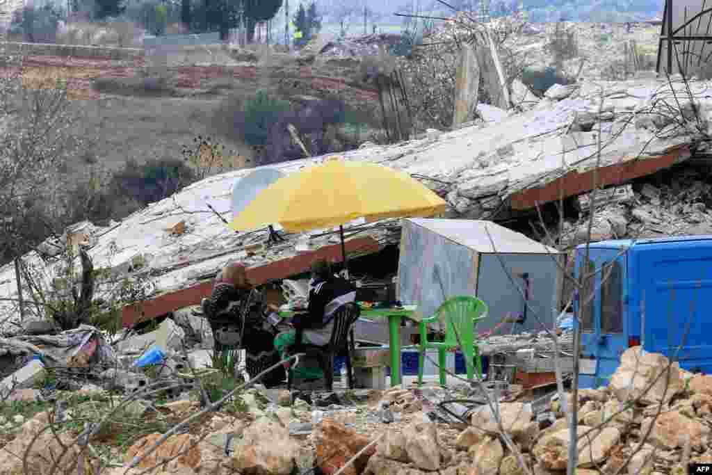 People sit around a table, set up atop the rubble of their house that was destroyed during the recent war between Israel and Hezbollah, in the village of al Jibbain in southern Lebanon.