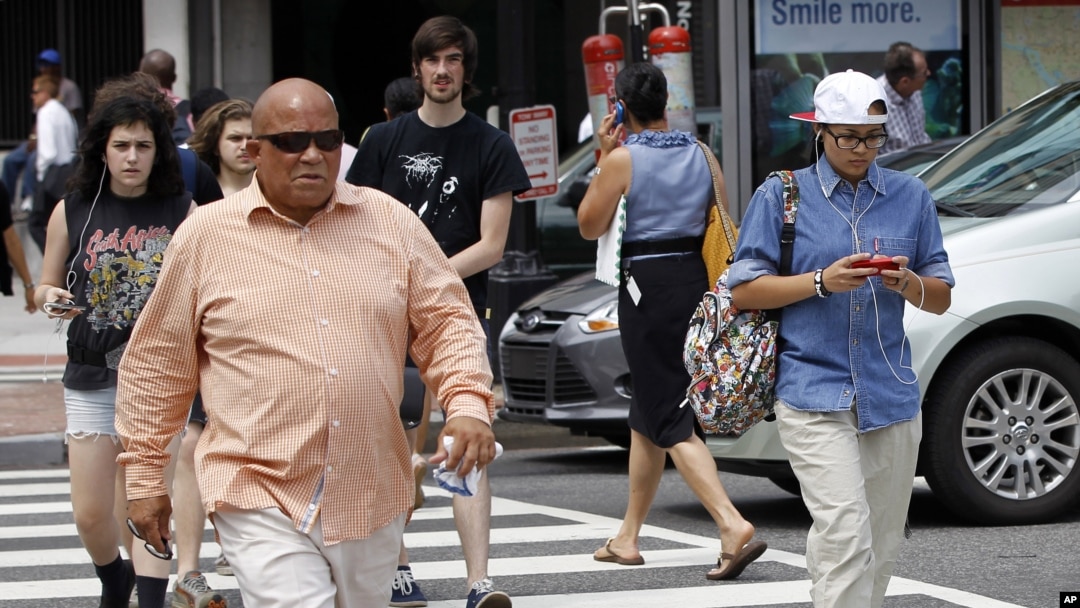Seorang pria menyeberang jalan di Washington sambil mengetik pesan teks di ponselnya (Foto: dok/ AP Photo/Pablo Martinez Monsivais)