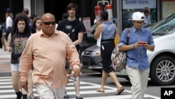 Seorang pria menyeberang jalan di Washington sambil mengetik pesan teks di ponselnya (Foto: dok/ AP Photo/Pablo Martinez Monsivais)