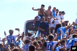 Pemain timnas Argentina antara lain Leandro Paredes, Rodrigo De Paul, Lionel Messi dan Nicolas Otamendi duduk di atas bus dalam parade kemenangan Piala Dunia di Buenos Aires, Selasa (20/12).