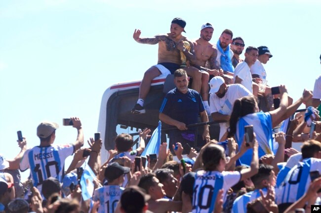 Pemain timnas Argentina antara lain Leandro Paredes, Rodrigo De Paul, Lionel Messi dan Nicolas Otamendi duduk di atas bus dalam parade kemenangan Piala Dunia di Buenos Aires, Selasa (20/12).