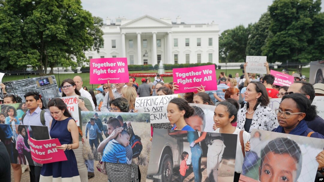 People hold up signs and photographs during a demonstration opposed to the White House policy that separated more than 2,300 children from their parents over the past several weeks in front of the White House in Washington, June 21, 2018.